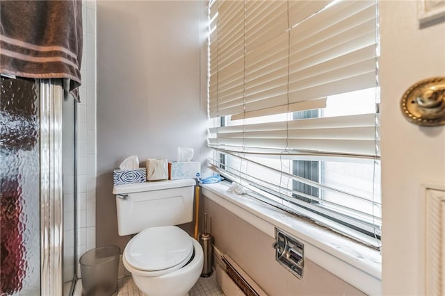 bathroom featuring tile patterned flooring, toilet, and a baseboard heating unit