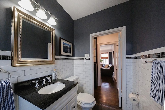 bathroom featuring vanity, wood-type flooring, tile walls, and toilet