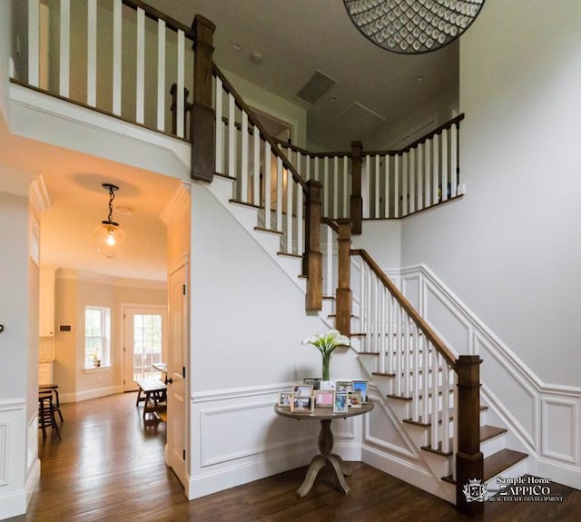 staircase with wood-type flooring and ornamental molding