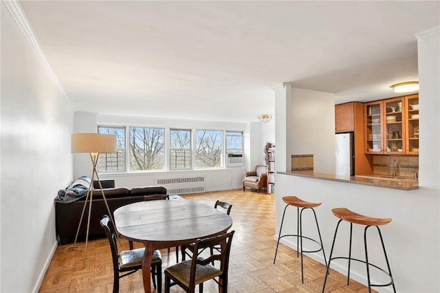 dining space with cooling unit, crown molding, radiator, and light parquet flooring