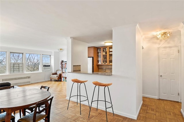 kitchen with kitchen peninsula, cooling unit, radiator heating unit, light parquet flooring, and white fridge