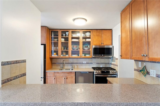 kitchen with sink, light stone countertops, stainless steel appliances, and tasteful backsplash