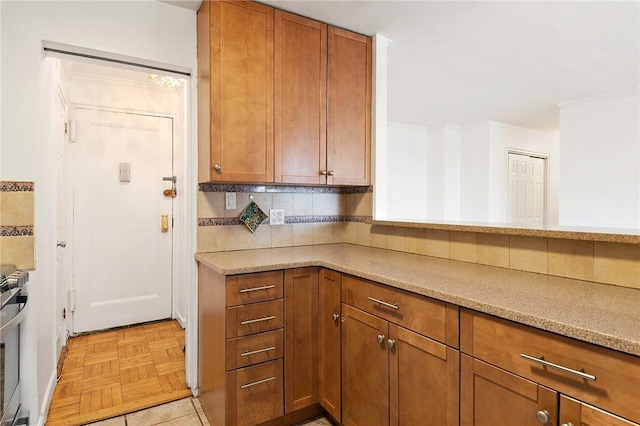 kitchen with stainless steel range oven, light stone counters, backsplash, and light parquet floors