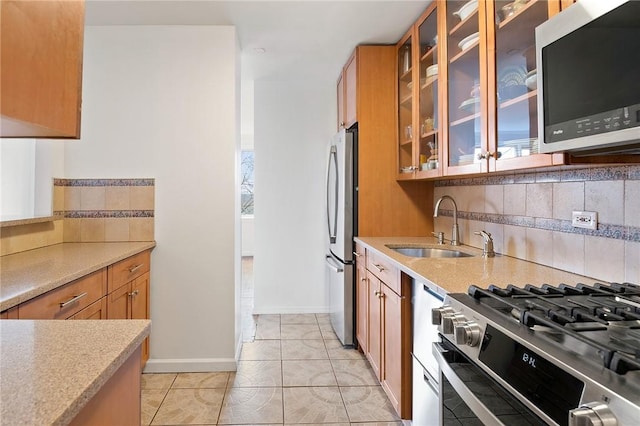 kitchen featuring decorative backsplash, appliances with stainless steel finishes, a wealth of natural light, sink, and light tile patterned floors