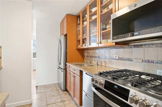 kitchen with light tile patterned floors, stainless steel appliances, tasteful backsplash, and sink