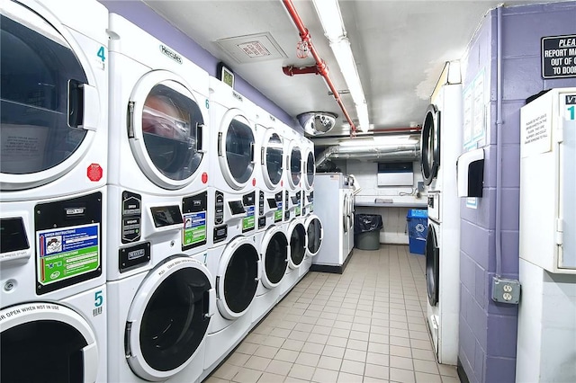 laundry area with light tile patterned floors, stacked washer / dryer, and washing machine and clothes dryer