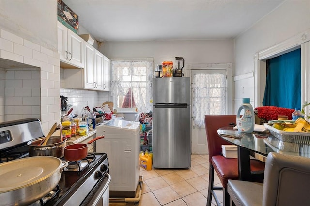 kitchen with white cabinetry, stainless steel appliances, light tile patterned floors, and tasteful backsplash