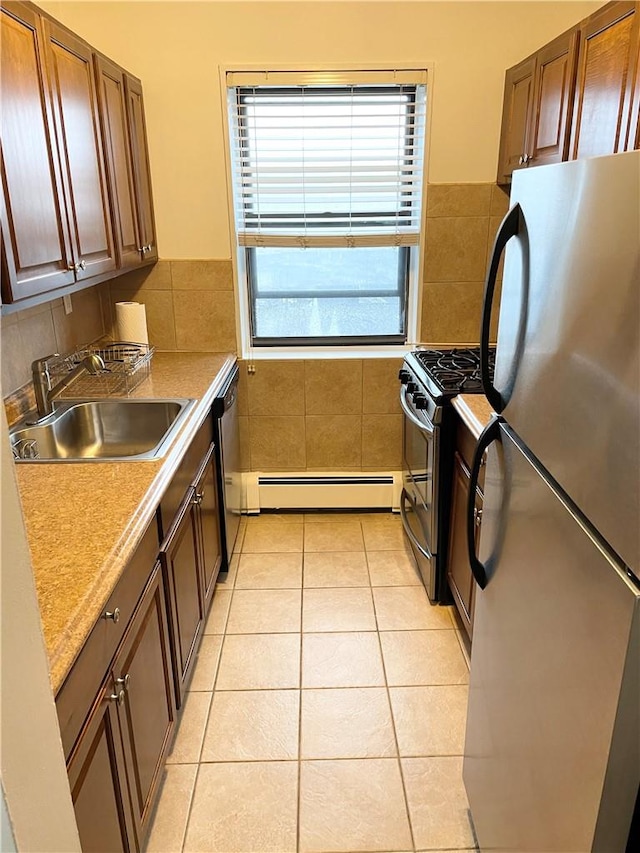 kitchen featuring baseboard heating, sink, light tile patterned flooring, and appliances with stainless steel finishes