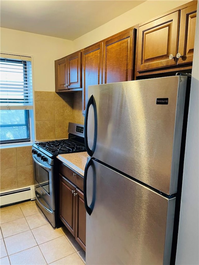 kitchen with baseboard heating, backsplash, light tile patterned floors, and stainless steel appliances