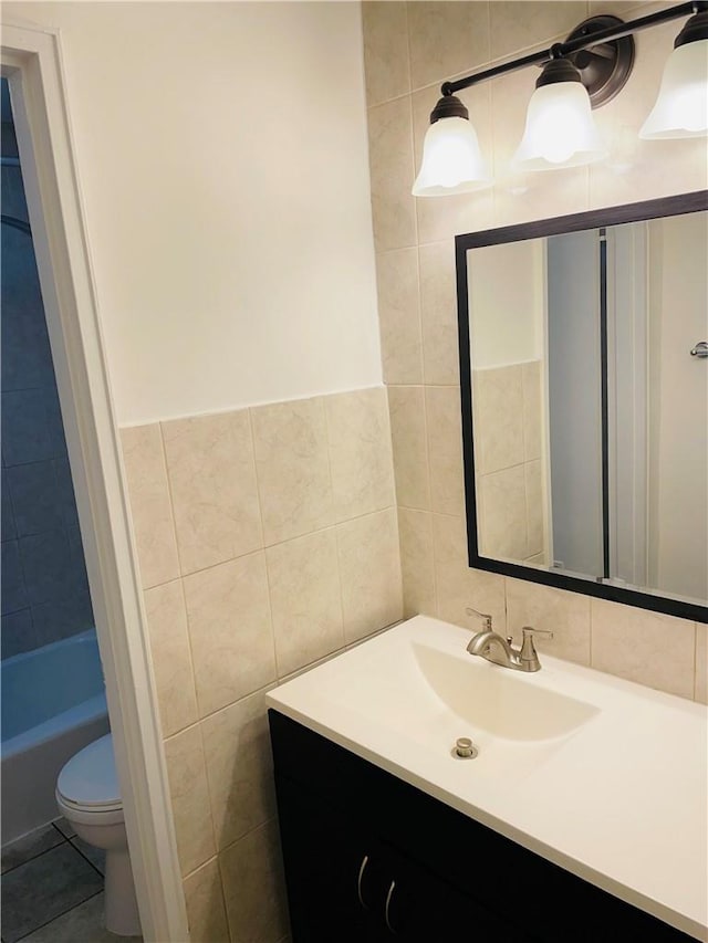 bathroom featuring vanity, toilet, and tile walls