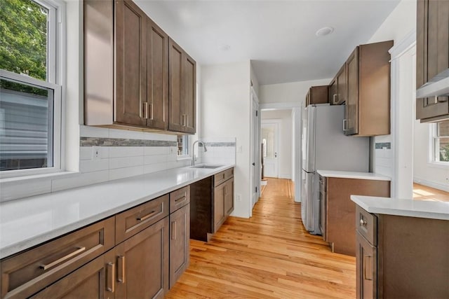 kitchen featuring plenty of natural light, decorative backsplash, sink, and light hardwood / wood-style flooring