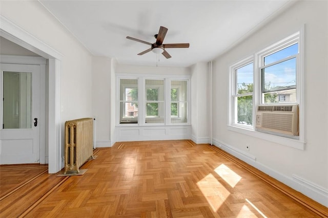 unfurnished room featuring ceiling fan, radiator heating unit, and light parquet flooring