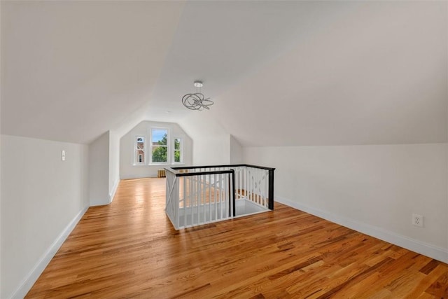 bonus room with light wood-type flooring and lofted ceiling