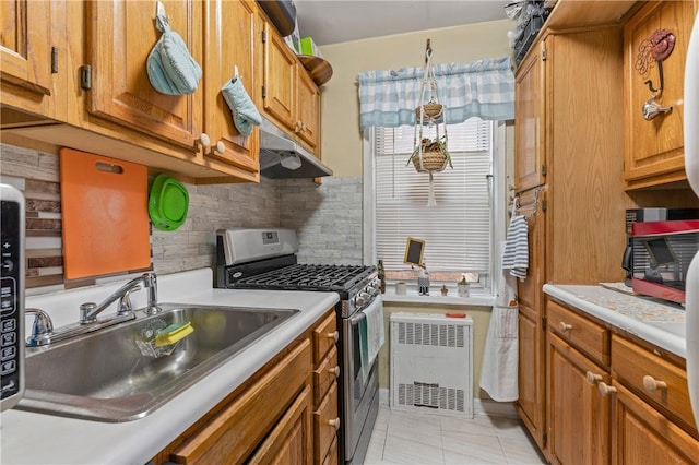 kitchen featuring backsplash, sink, light tile patterned floors, hanging light fixtures, and stainless steel range with gas stovetop