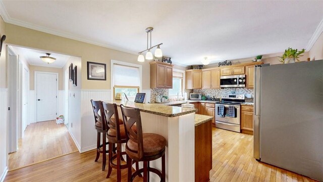 59 Ludingtonville Rd, Holmes, NY 12531 - kitchen featuring appliances with stainless steel finishes, a peninsula, light wood-style floors, wainscoting, and a kitchen breakfast bar