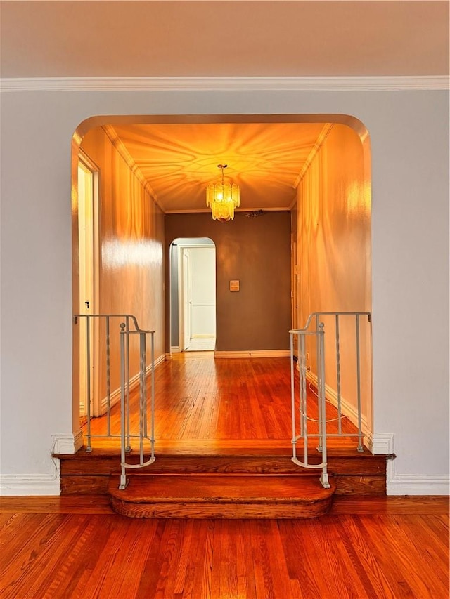 hall featuring hardwood / wood-style flooring, crown molding, and a chandelier