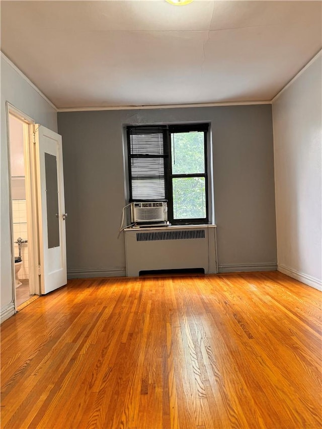 spare room featuring cooling unit, light wood-type flooring, radiator heating unit, and ornamental molding