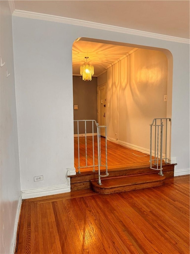 unfurnished room with a chandelier, wood-type flooring, and crown molding