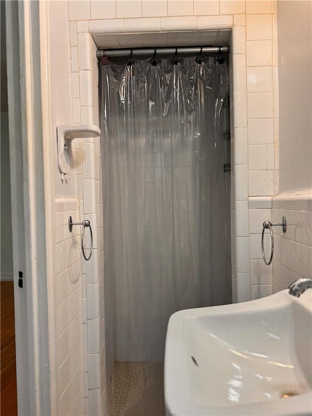 bathroom with a shower, sink, and tile walls