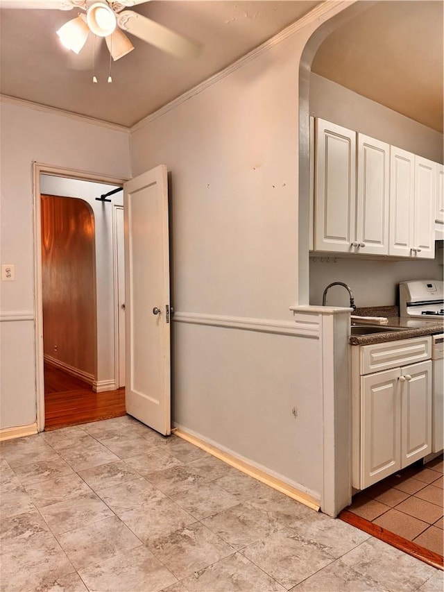 kitchen featuring white range, sink, crown molding, ceiling fan, and white cabinetry