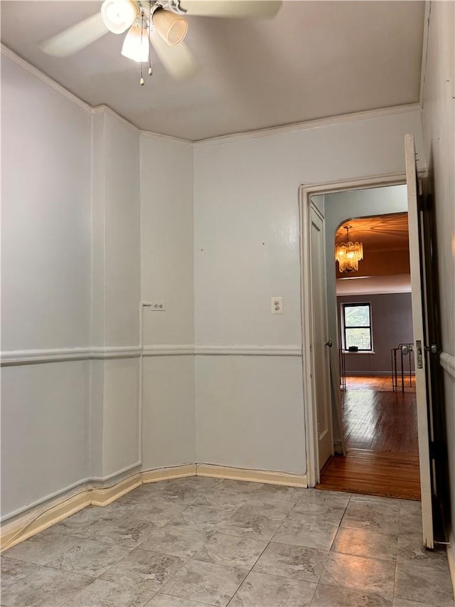 spare room with hardwood / wood-style floors, ceiling fan with notable chandelier, and ornamental molding