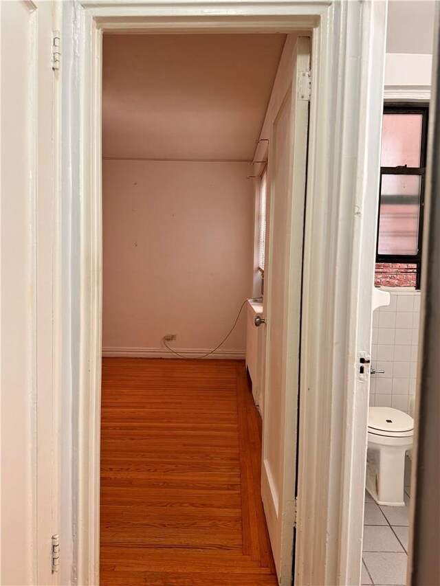 corridor with light wood-type flooring and tile walls