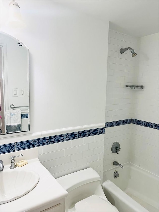 full bathroom featuring toilet, vanity, tile walls, and tiled shower / bath