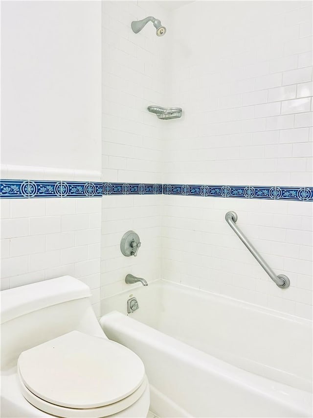 bathroom featuring tiled shower / bath, tile walls, and toilet