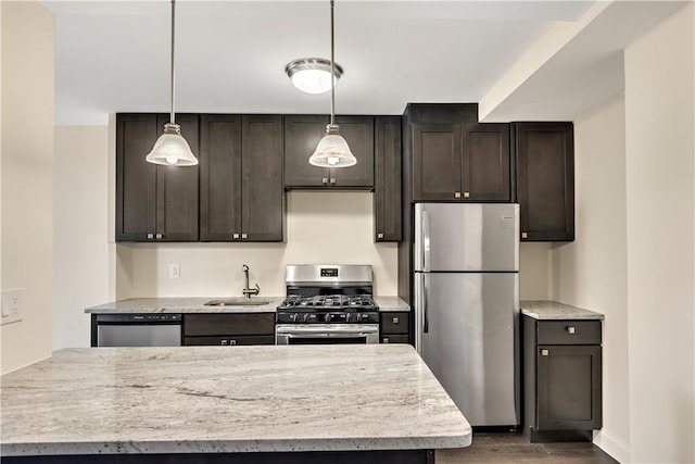 kitchen with appliances with stainless steel finishes, dark hardwood / wood-style flooring, light stone counters, sink, and pendant lighting