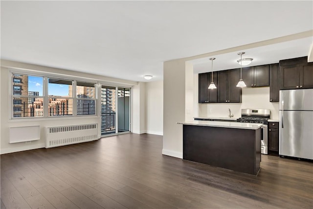 kitchen with pendant lighting, radiator heating unit, stainless steel appliances, and dark hardwood / wood-style flooring