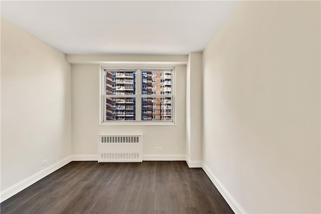 spare room featuring radiator and dark wood-type flooring