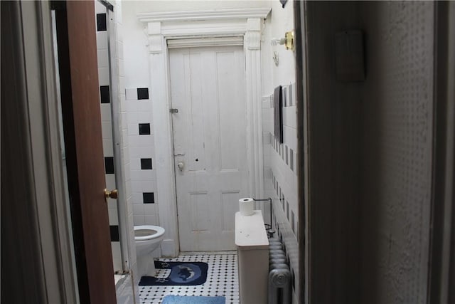 bathroom with toilet and tile walls