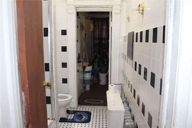 bathroom featuring tile patterned flooring, tile walls, and toilet