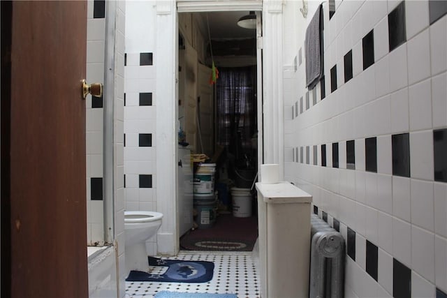 bathroom with tile patterned floors, toilet, and tile walls