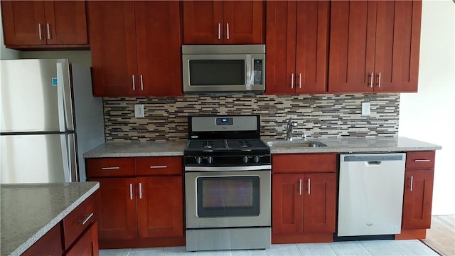 kitchen featuring decorative backsplash, appliances with stainless steel finishes, light stone counters, and sink