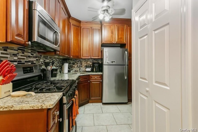 kitchen with decorative backsplash, light tile patterned floors, light stone countertops, and appliances with stainless steel finishes