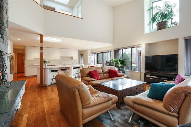 living room with a high ceiling, light hardwood / wood-style floors, and sink