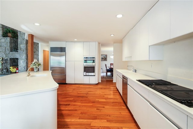 kitchen featuring sink, white cabinets, light hardwood / wood-style floors, and appliances with stainless steel finishes