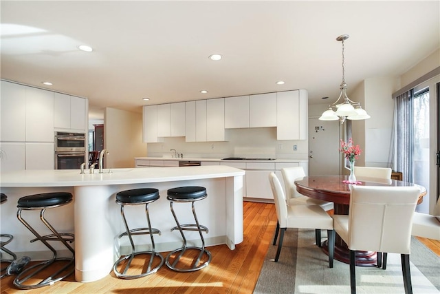 kitchen featuring light hardwood / wood-style floors, black gas stovetop, white cabinetry, and double oven