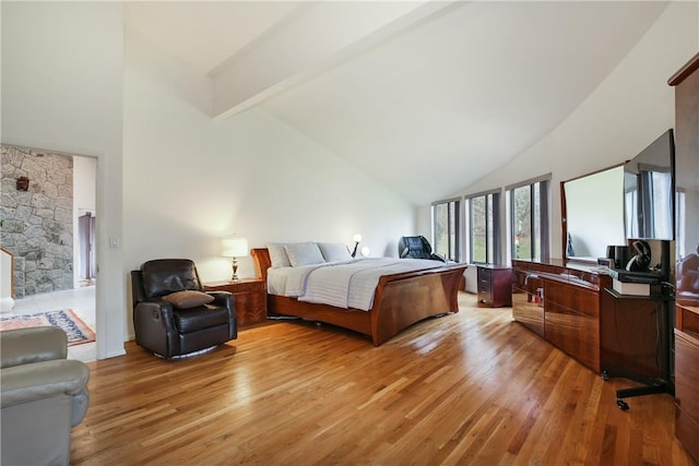 bedroom with beamed ceiling, high vaulted ceiling, and light hardwood / wood-style flooring