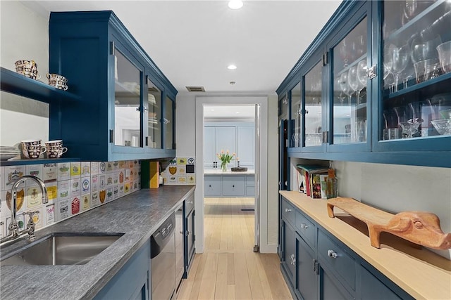 bar featuring blue cabinetry, sink, stainless steel dishwasher, and light hardwood / wood-style flooring