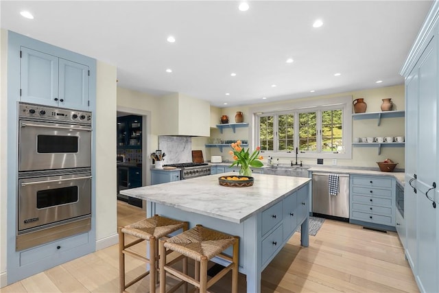 kitchen with a center island, stainless steel appliances, blue cabinets, and light hardwood / wood-style floors