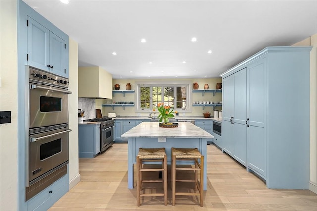 kitchen with light hardwood / wood-style flooring, a kitchen island, blue cabinetry, and stainless steel appliances