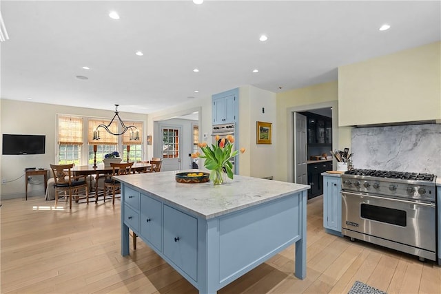 kitchen featuring a center island, blue cabinets, light hardwood / wood-style flooring, appliances with stainless steel finishes, and decorative light fixtures