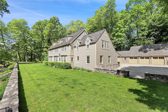 rear view of property with a garage, an outdoor structure, and a yard