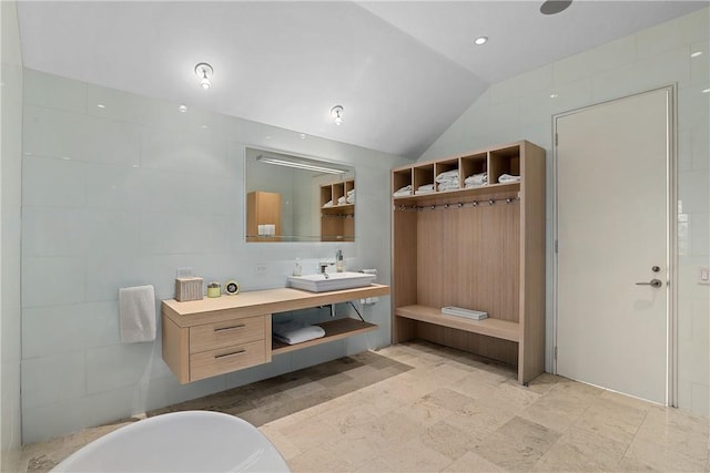 bathroom featuring vanity, lofted ceiling, and a bath