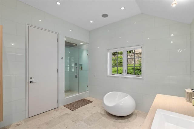 bathroom featuring separate shower and tub, vaulted ceiling, and tile walls