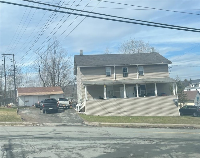 view of front facade with a porch, a garage, and an outbuilding