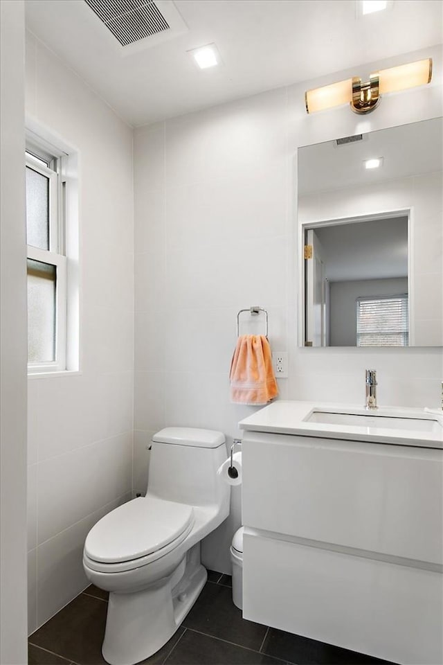 bathroom with tile patterned flooring, vanity, tile walls, and toilet