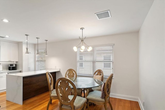 dining space featuring light hardwood / wood-style floors and an inviting chandelier